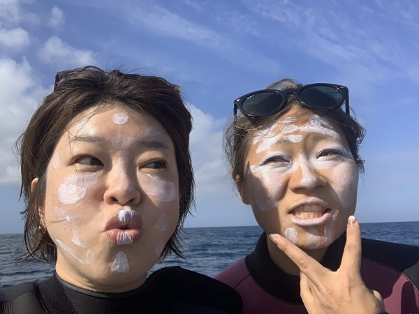 女性のダイバー2人が顔に日焼け止めを塗っている様子