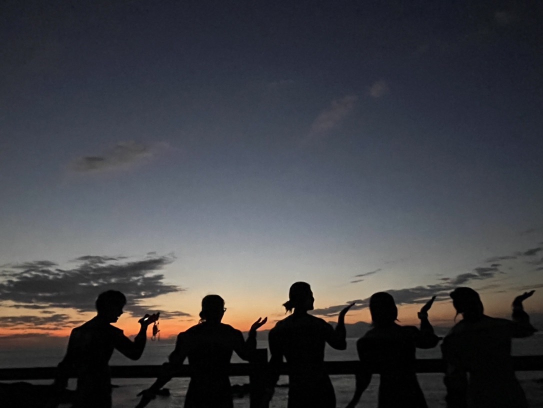 夕日をバックにダイバー５人が後ろ向きになってポーズを決めている写真