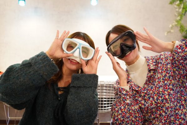 ダイビング器材のマスクを顔に合わせて写真を撮る女性2人
