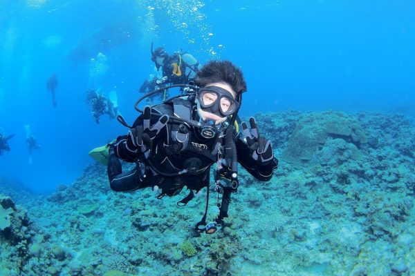 海の中で中世浮力を取ってカメラにポーズをする女性ダイバー