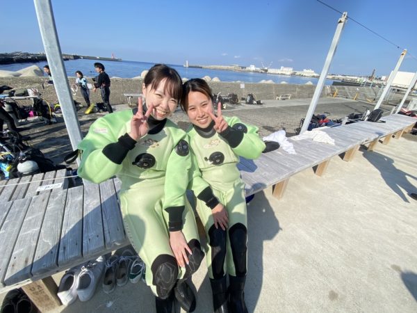 2人の女性ダイバーが海の前でピースサイン