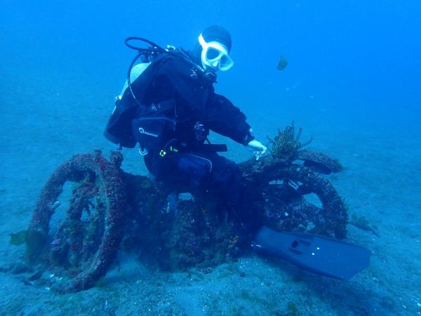 海の中のバイクのオブジェに乗る男性ダイバー