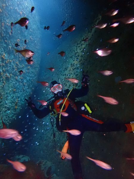魚の群れと一緒に写真に写る女性ダイバー