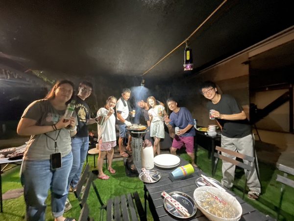 BBQをしながら集合写真を撮る複数の男女