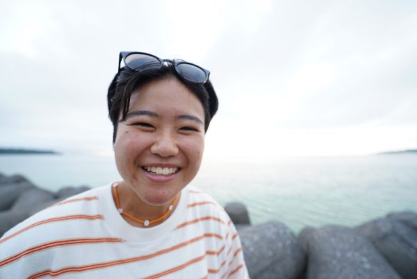 サングラスを着けた女性が海の前で笑っている様子