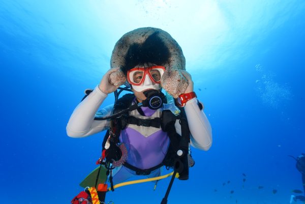 海の中でナマコを頭に乗せている女性