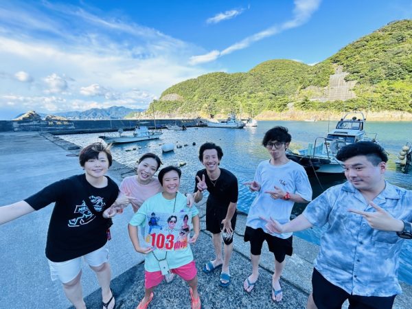 海の前で複数の男女が集合写真