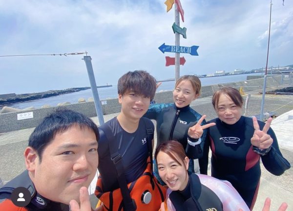 海の前で複数のダイバーが集合写真