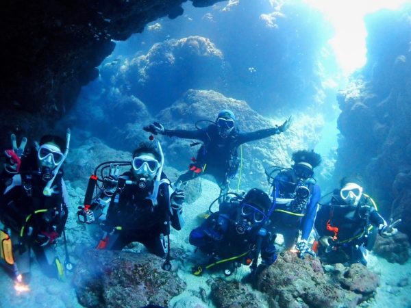 海の洞窟の中で集合写真を撮る複数のダイバー
