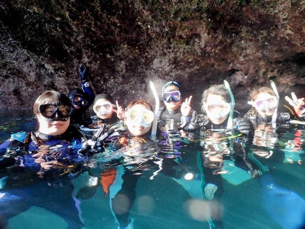 水面から顏を出して記念写真を撮る複数のダイバー