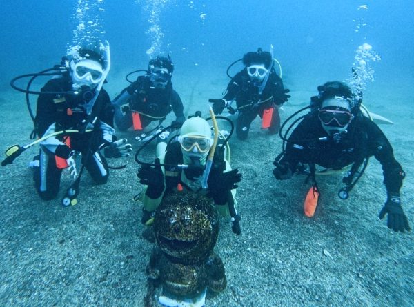 水中のドラえもんと複数のダイバーが集合写真。