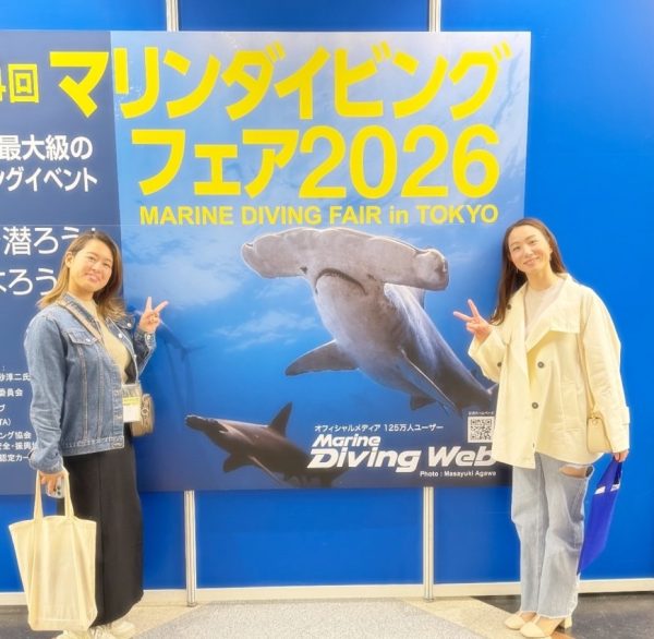 マリンダイビングフェアのポスターの前で写真を撮る女性2名