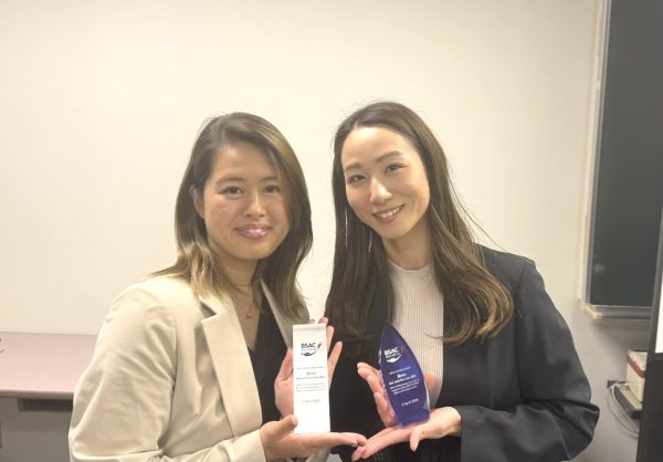 表彰の盾を持って記念写真を撮る女性2名